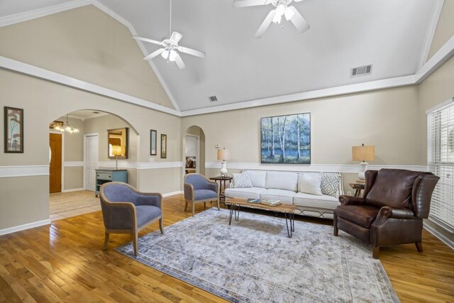 living room with ceiling fan with notable chandelier, visible vents, wood finished floors, and arched walkways