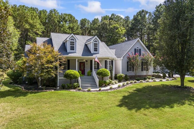 cape cod-style house featuring a front yard, covered porch, and roof with shingles