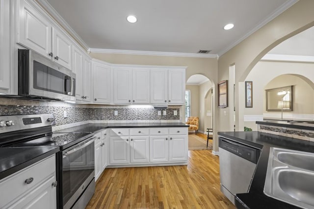 kitchen featuring light wood-type flooring, white cabinetry, stainless steel appliances, and decorative backsplash