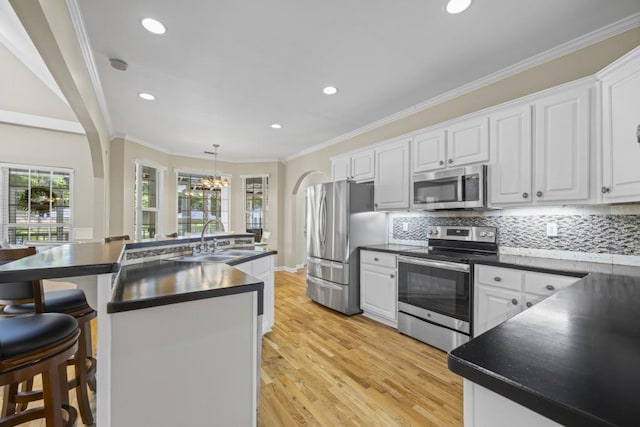 kitchen with a kitchen island with sink, sink, stainless steel appliances, and white cabinets