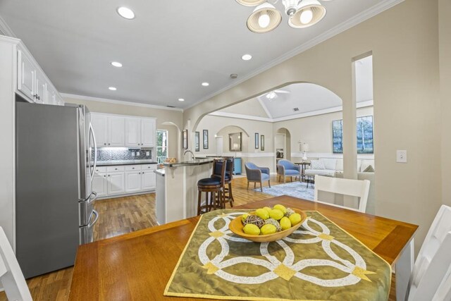 dining space with crown molding, wood finished floors, arched walkways, and a chandelier