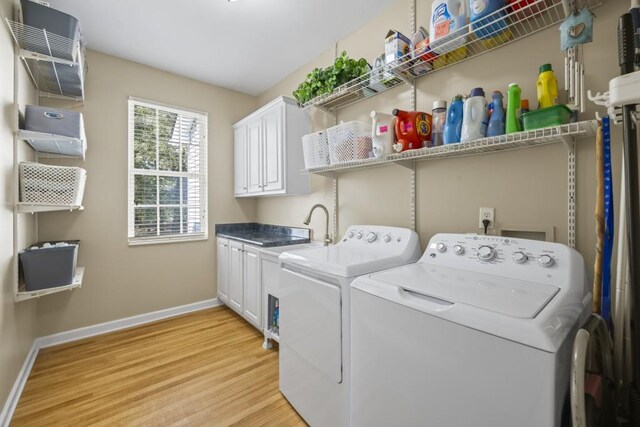 clothes washing area with washer and clothes dryer, light wood-style flooring, baseboards, an AC wall unit, and cabinet space