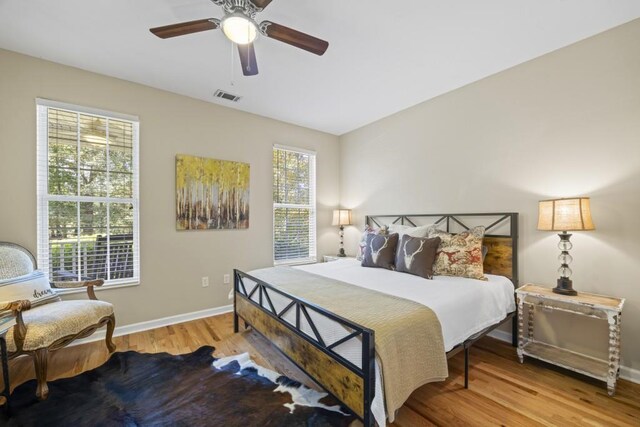 bedroom with baseboards, visible vents, wood finished floors, and a ceiling fan