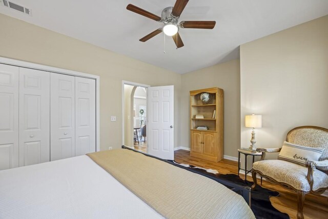 bedroom with vaulted ceiling, visible vents, a ceiling fan, a closet, and wood finished floors
