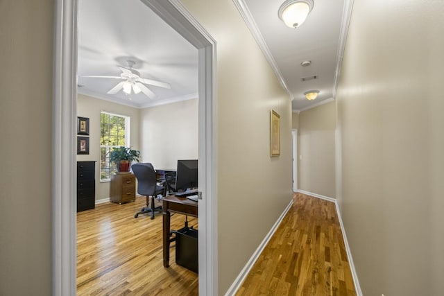 corridor with light hardwood / wood-style flooring and ornamental molding