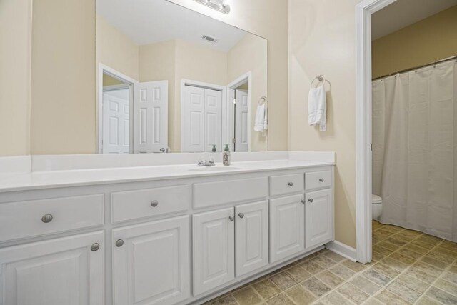 bathroom featuring baseboards, visible vents, toilet, and vanity