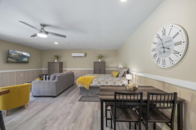 dining area featuring a wall mounted AC, ceiling fan, and wood-type flooring