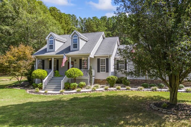 cape cod home with covered porch, a shingled roof, and a front lawn