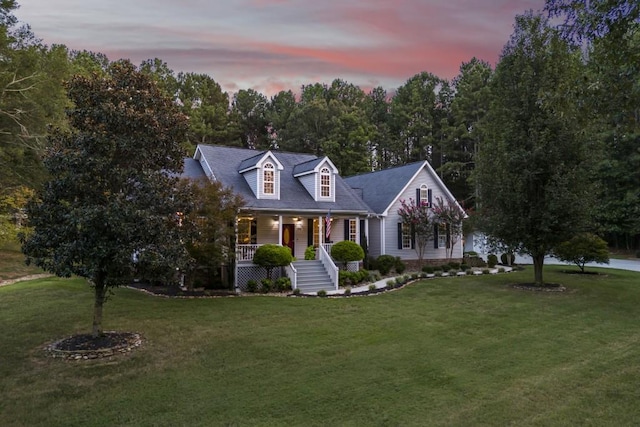 cape cod house with a lawn and covered porch