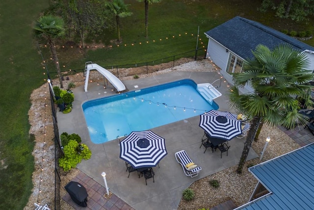 view of swimming pool with a water slide, a patio area, and a yard