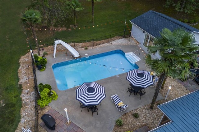 view of swimming pool with a fenced backyard, a water slide, a patio area, and a fenced in pool