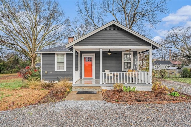 bungalow with a porch, a chimney, and a ceiling fan