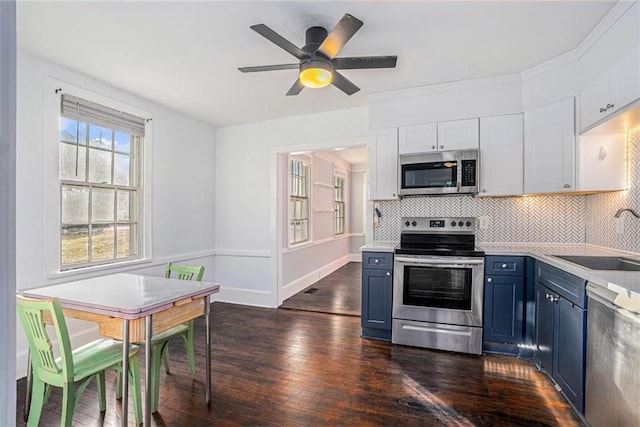 kitchen featuring tasteful backsplash, dark wood-style floors, stainless steel appliances, blue cabinetry, and a sink