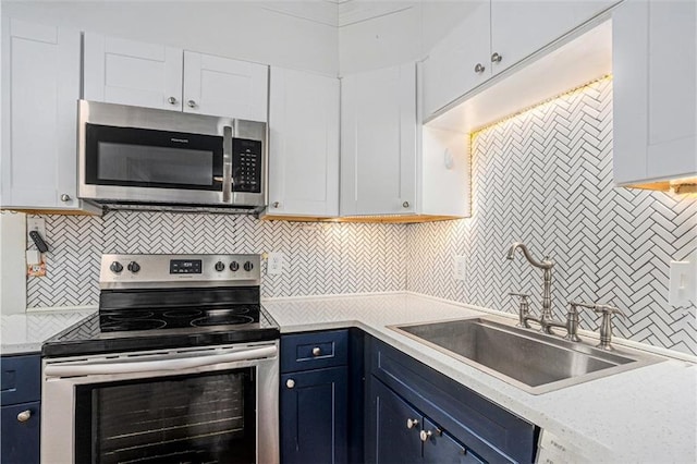 kitchen featuring blue cabinets, stainless steel appliances, a sink, white cabinets, and light countertops