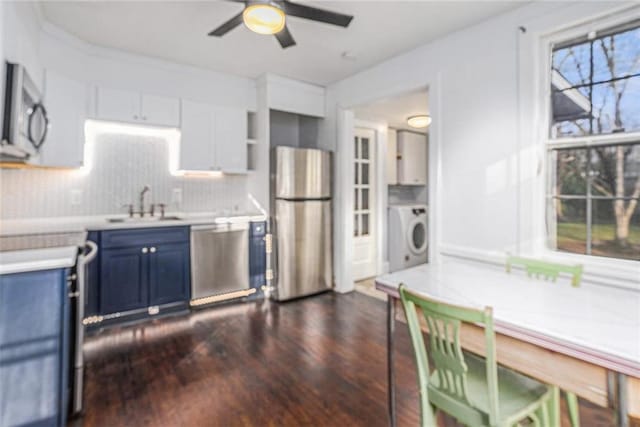 kitchen with appliances with stainless steel finishes, washer / clothes dryer, blue cabinets, light countertops, and a sink