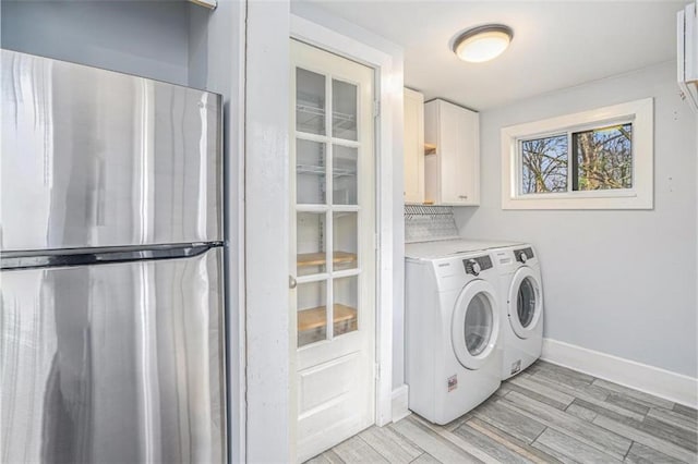 washroom featuring cabinet space, baseboards, washer and clothes dryer, and light wood finished floors