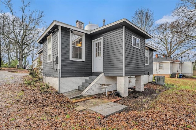 rear view of house featuring a chimney and central AC