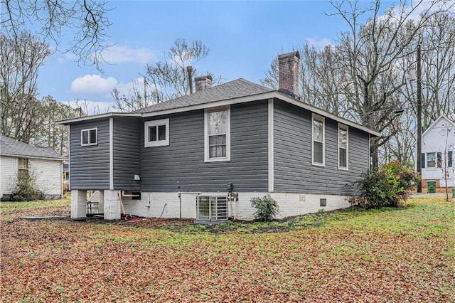 back of property with crawl space, a yard, a chimney, and central air condition unit