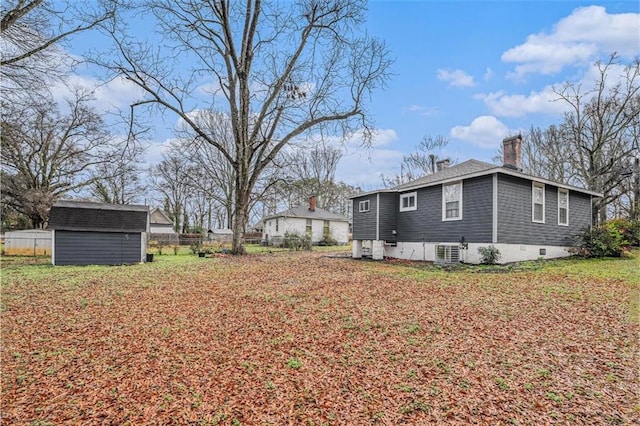 exterior space with a chimney, a storage unit, fence, cooling unit, and an outdoor structure