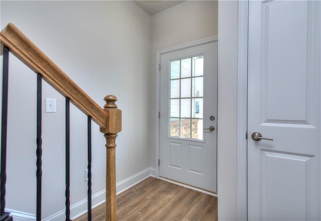 doorway with stairway, wood finished floors, and baseboards