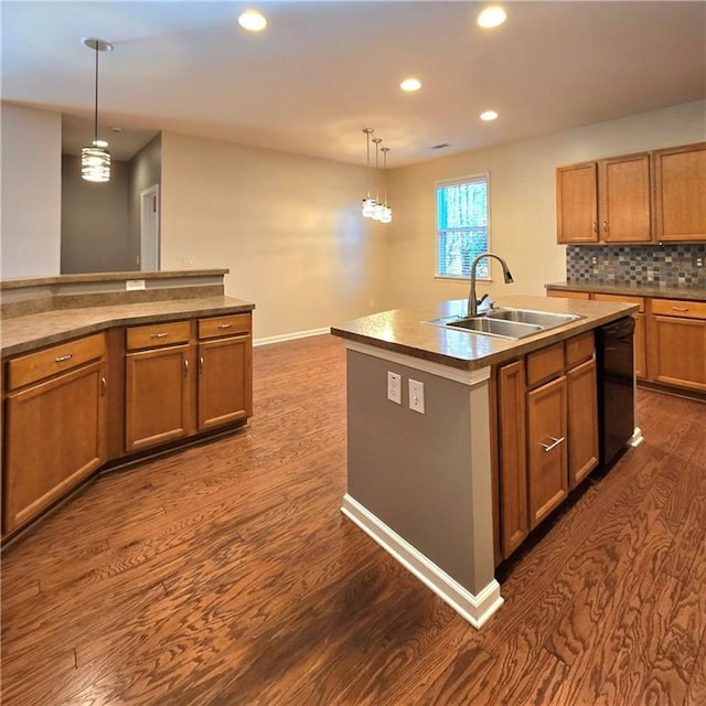 kitchen with a center island with sink, dark wood-type flooring, dishwasher, pendant lighting, and sink