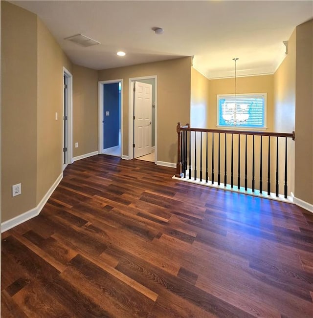 empty room featuring dark wood-type flooring and a chandelier