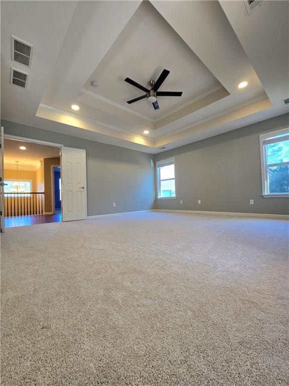 carpeted spare room with ceiling fan and a tray ceiling