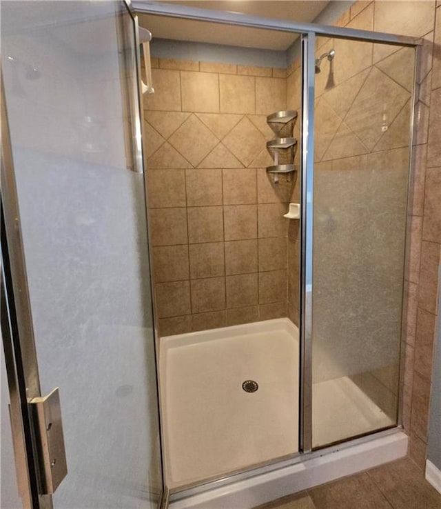 bathroom with a shower with door and tile patterned flooring