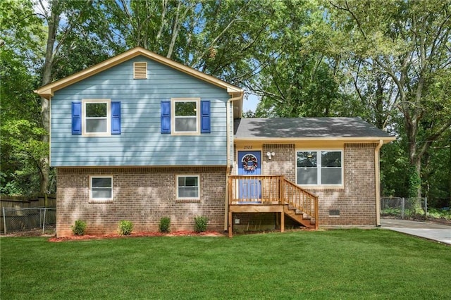 back of property with crawl space, brick siding, a lawn, and fence