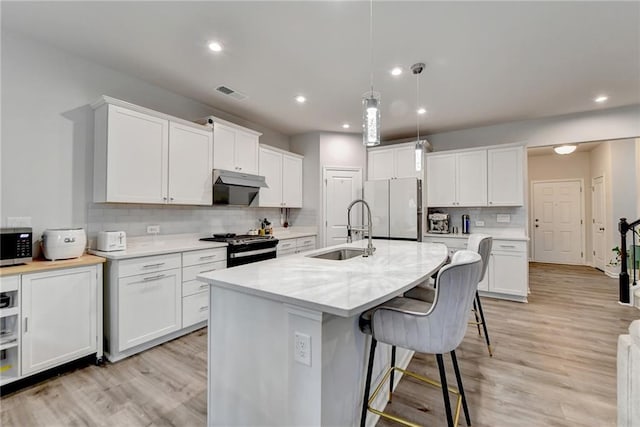 5452 Fountainhead Ln, Auburn, GA 30011 - kitchen with visible vents, light wood-style floors, tasteful backsplash, a sink, and appliances with stainless steel finishes