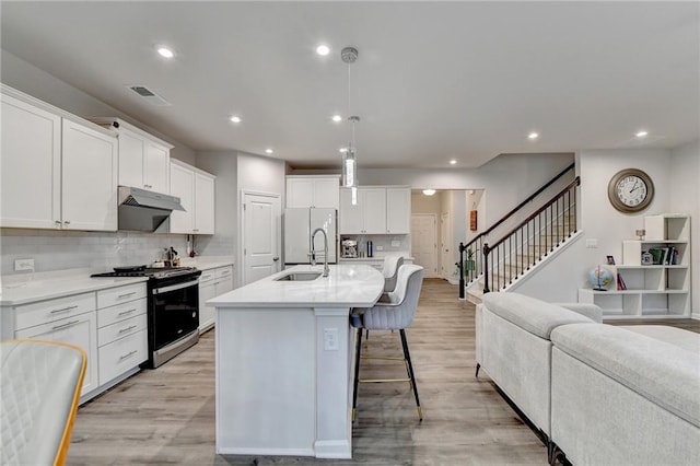5452 Fountainhead Ln, Auburn, GA 30011 - kitchen with a sink, freestanding refrigerator, a breakfast bar, under cabinet range hood, and gas range oven