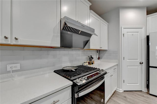 5452 Fountainhead Ln, Auburn, GA 30011 - kitchen with light wood-style floors, light countertops, stainless steel gas stove, white cabinetry, and under cabinet range hood