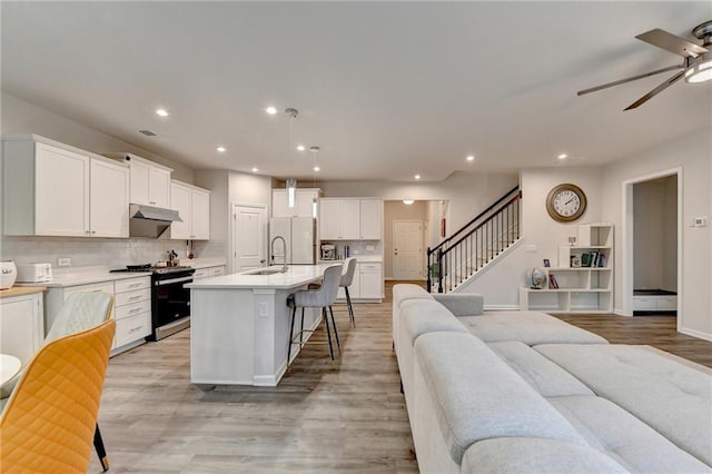 5452 Fountainhead Ln, Auburn, GA 30011 - kitchen featuring a ceiling fan, a kitchen breakfast bar, stainless steel range with gas cooktop, under cabinet range hood, and a sink