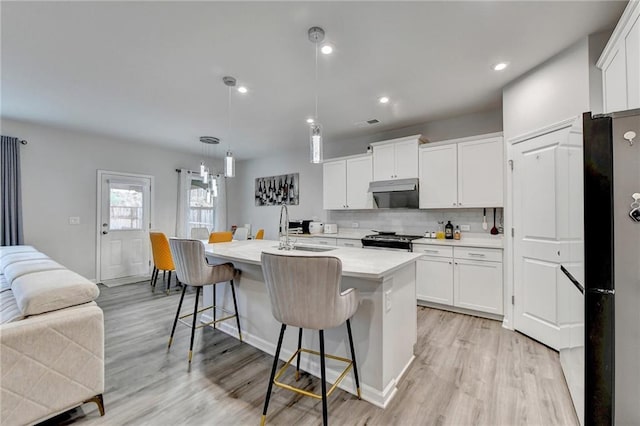 5452 Fountainhead Ln, Auburn, GA 30011 - kitchen with gas range, tasteful backsplash, a sink, light countertops, and under cabinet range hood