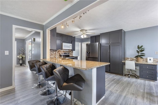 1433 Janice Ct SW, Lilburn, GA 30047 - kitchen with appliances with stainless steel finishes, light wood-type flooring, light stone countertops, a textured ceiling, and a kitchen breakfast bar