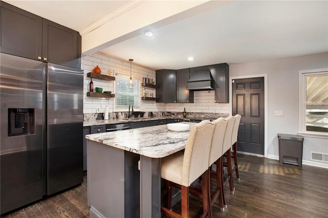 kitchen featuring a sink, visible vents, stainless steel refrigerator with ice dispenser, open shelves, and custom range hood