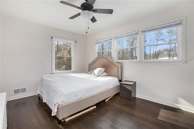 bedroom with ceiling fan, wood finished floors, visible vents, and baseboards