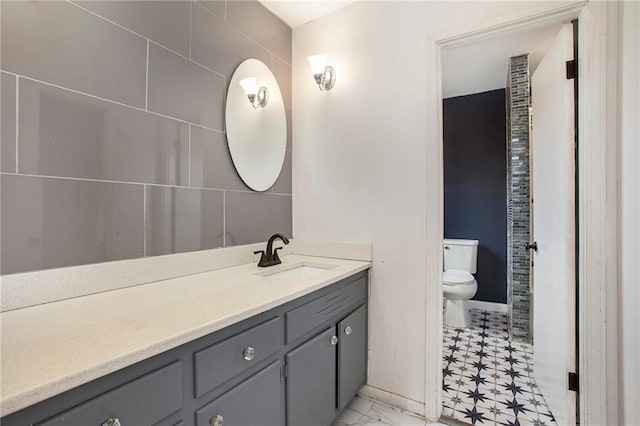 bathroom featuring toilet, baseboards, and vanity