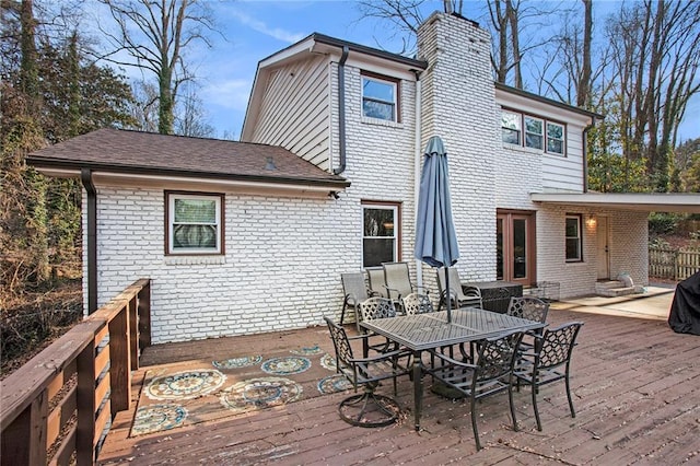 rear view of house with a deck, brick siding, and a chimney