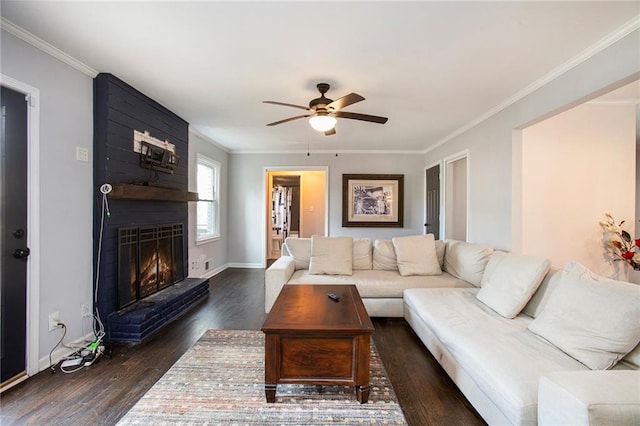 living room with a large fireplace, wood finished floors, and crown molding