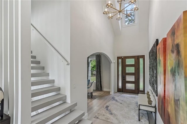 7540 Shadburn Ferry Rd, Cumming, GA 30041 - foyer entrance with arched walkways, a high ceiling, stairs, a chandelier, and wood finished floors