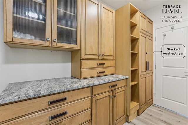 7540 Shadburn Ferry Rd, Cumming, GA 30041 - kitchen with open shelves, light stone countertops, light wood-type flooring, and glass insert cabinets