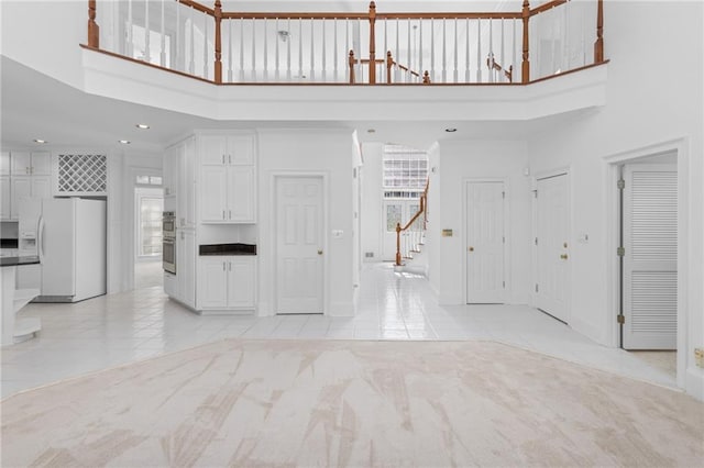unfurnished living room with a towering ceiling and light tile patterned flooring