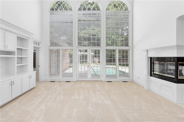 unfurnished living room featuring a multi sided fireplace and light carpet