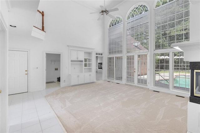 unfurnished living room featuring a wealth of natural light, light carpet, a high ceiling, and ceiling fan
