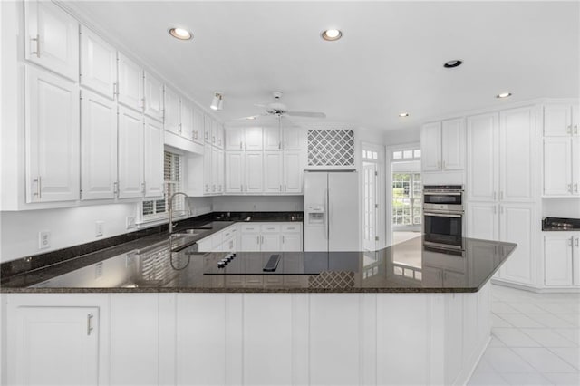 kitchen featuring sink, white fridge with ice dispenser, stainless steel double oven, light tile patterned floors, and white cabinets