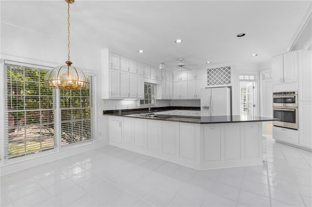 kitchen with light tile patterned flooring, white cabinets, decorative light fixtures, and white refrigerator with ice dispenser