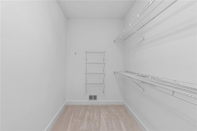 walk in closet with light carpet
