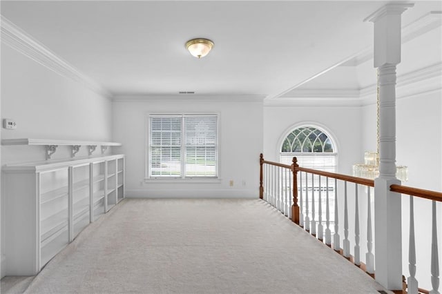 hall with a healthy amount of sunlight, ornamental molding, and light colored carpet