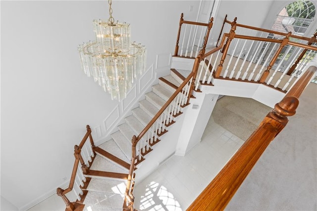 staircase with a notable chandelier and tile patterned floors